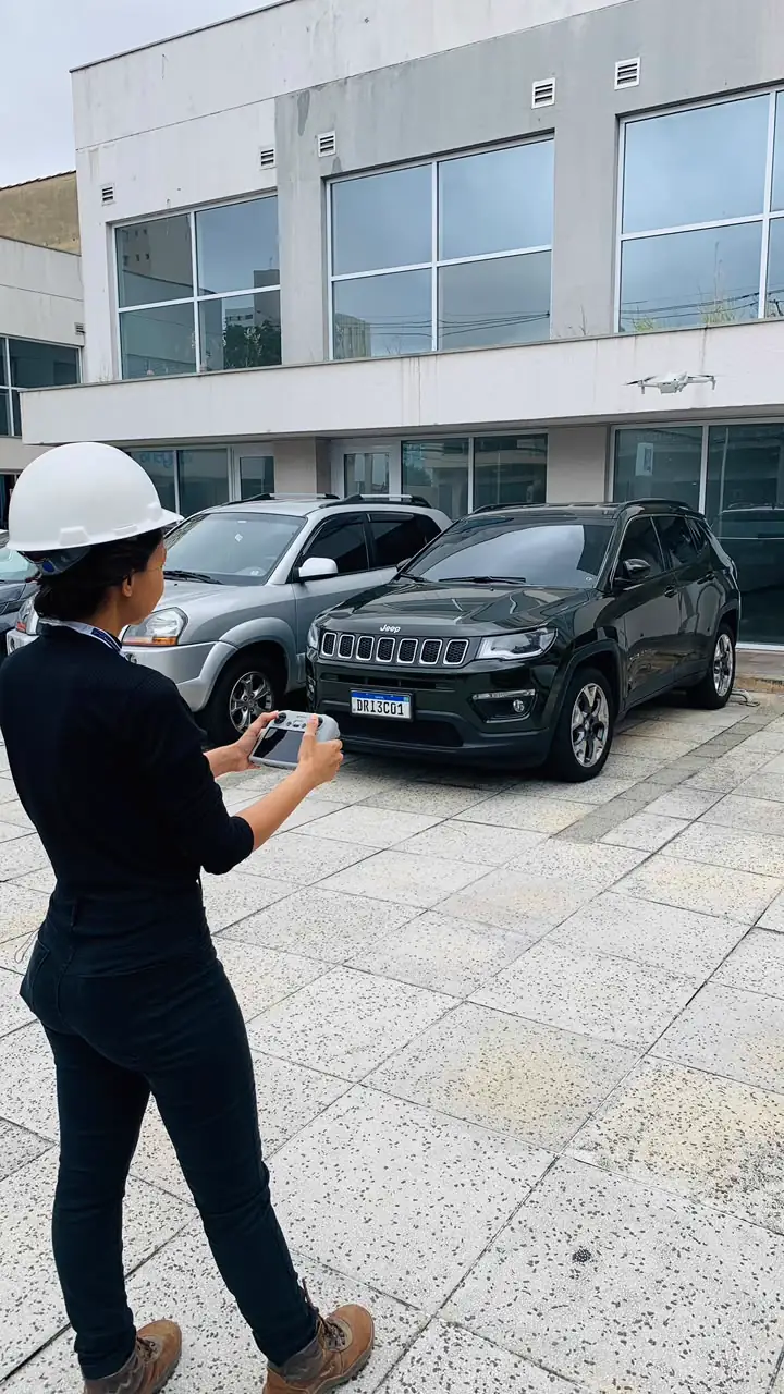 Bianca operando um drone em frente à fachada de um edifício comercial.